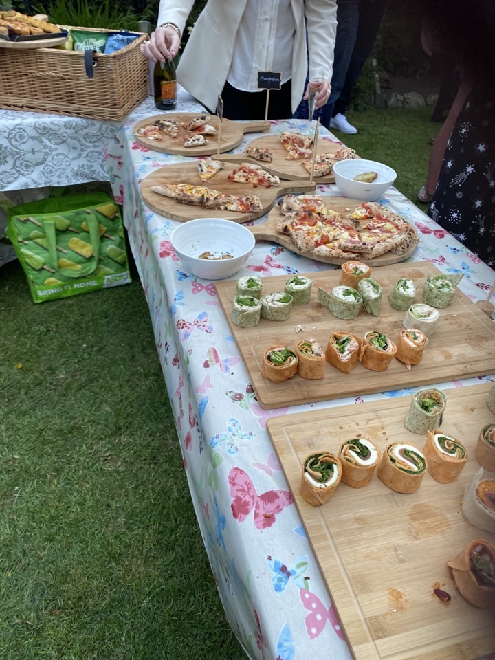 A pizza buffet table laid with sliced pizzas on wooden boards alongside boards of rolled wraps